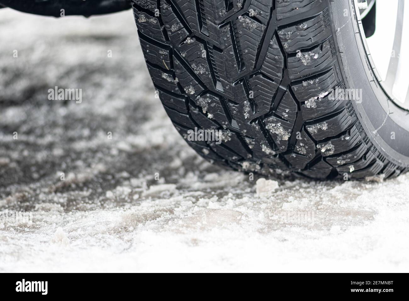 Close up winter tire of a car on the road covered by snow and ice driving in extreme cold Stock Photo