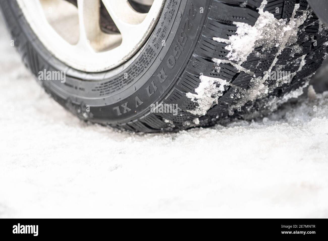 Close up winter tire of a car on the road covered by snow and ice driving in extreme cold Stock Photo
