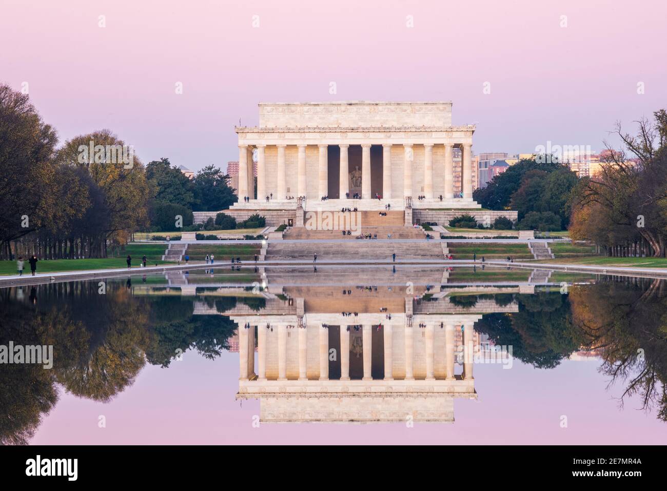 A pink sky and the ivory marble iconic Lincoln Memorial is mirrored in the Reflecting Pool on a crisp Autumn morning in Washington, DC. Located at the Stock Photo