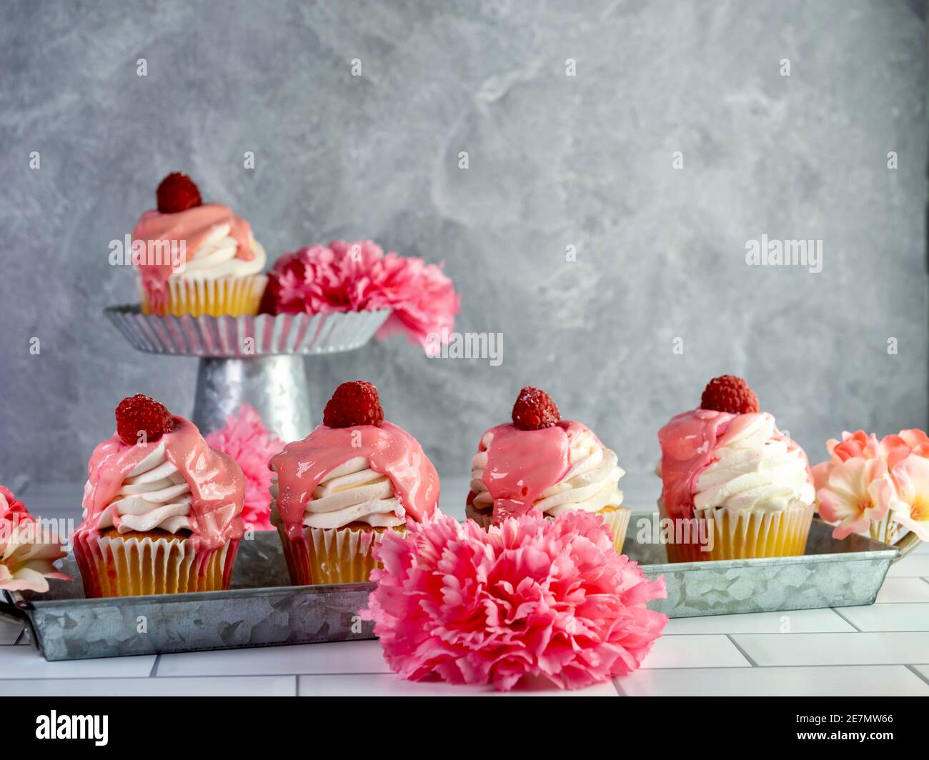 Raspberry cupcakes with white frosting and pink drizzle with a fresh ...