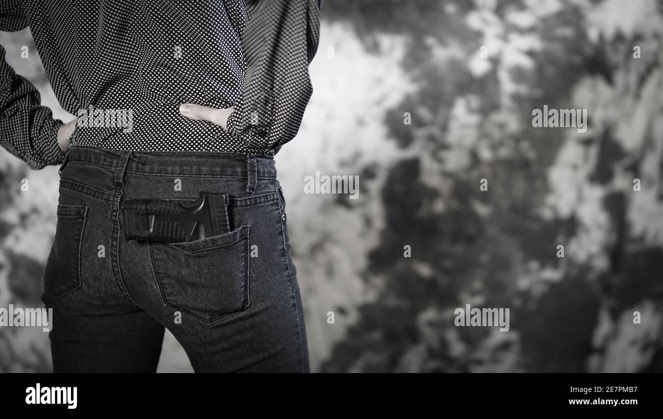 Woman with small handgun tucked in her back pocket. Women's personal defense and concealed carry concept Stock Photo