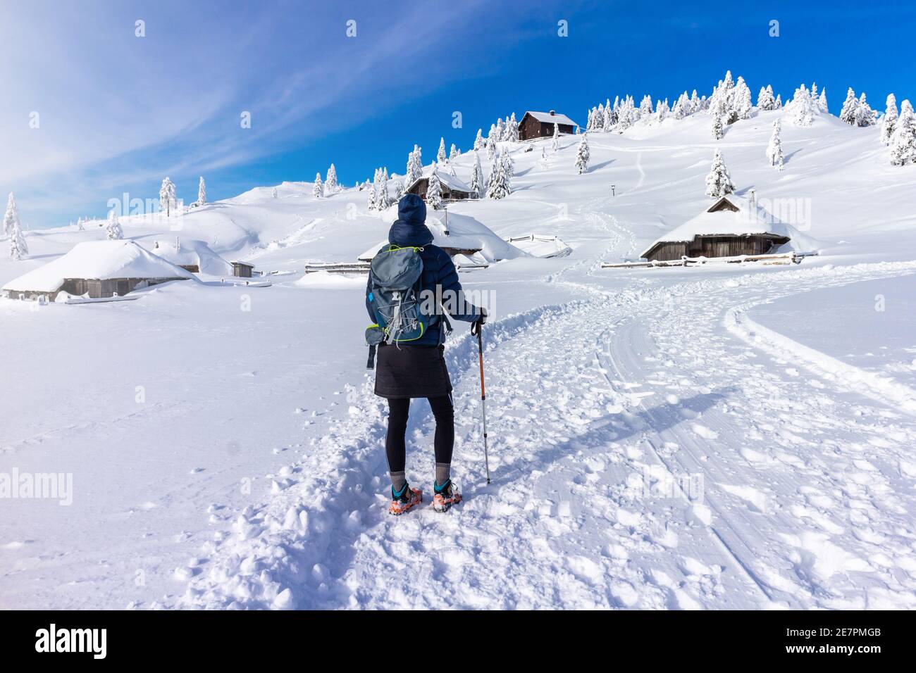Woman hiking in the mountains in winter time with snow wearing crampons, walking sticks and backpack. Stock Photo