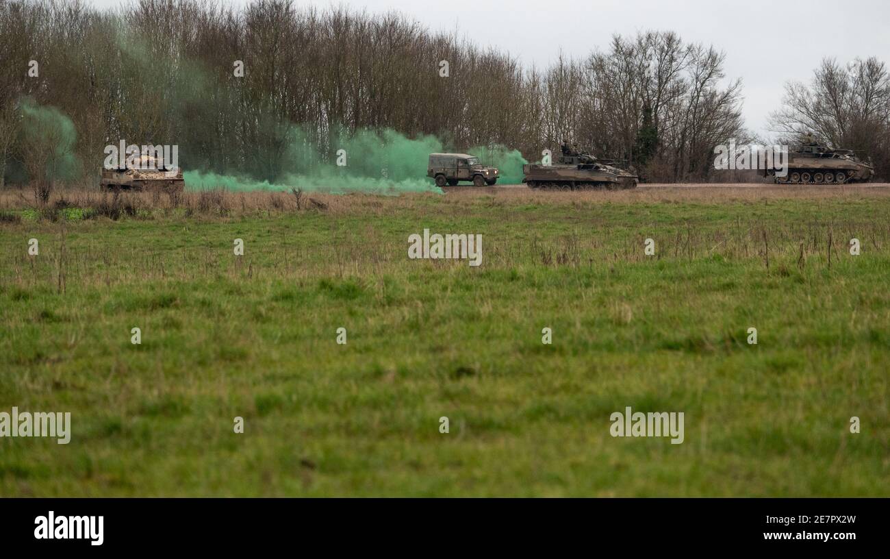 british army warrior FV510 army and Defender Wolf vehicles on exercise with deployed green smoke grenades Stock Photo