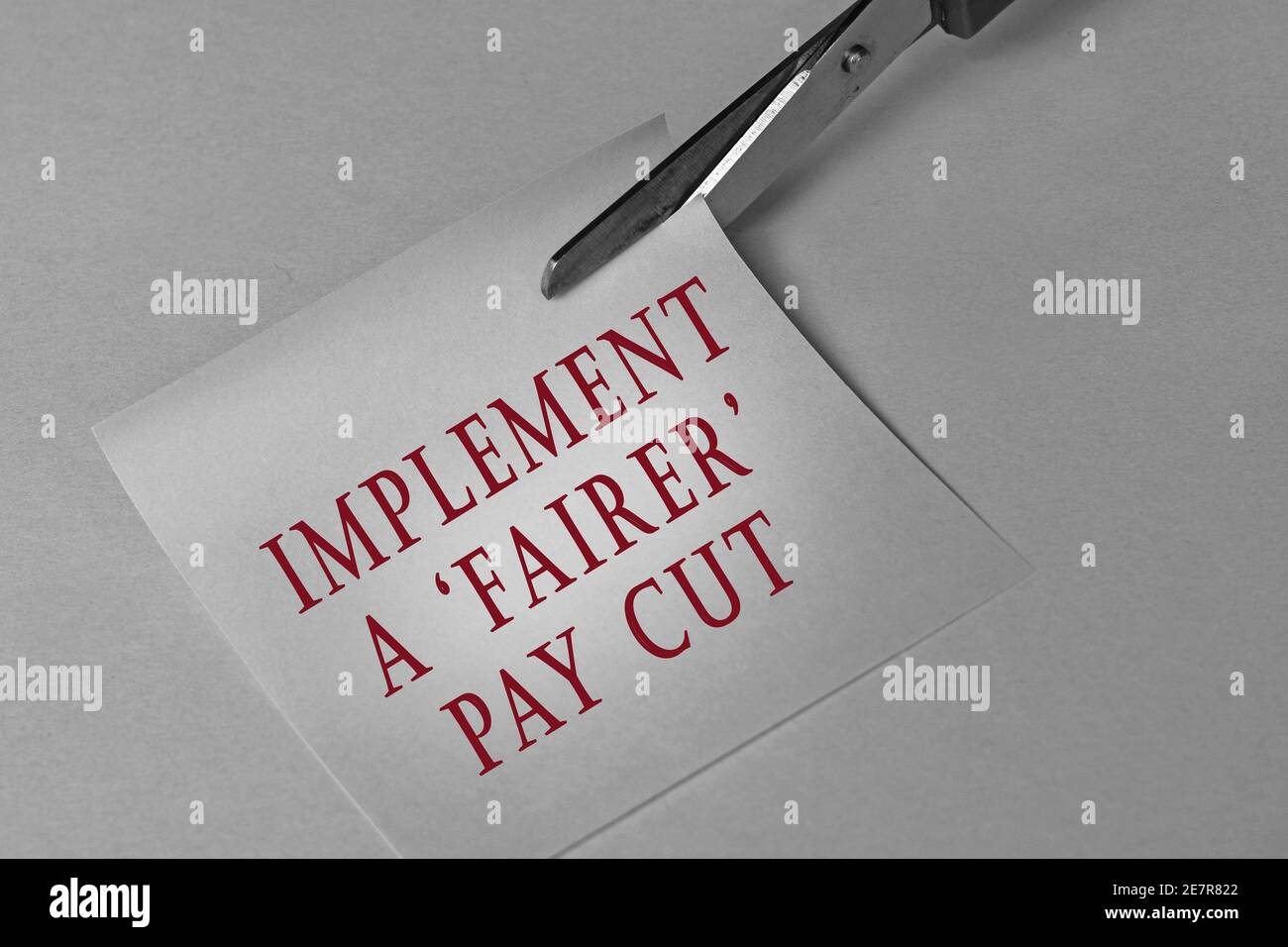 Scissors that cut notepad with text on white background. Business concepts, fair pay cut Stock Photo