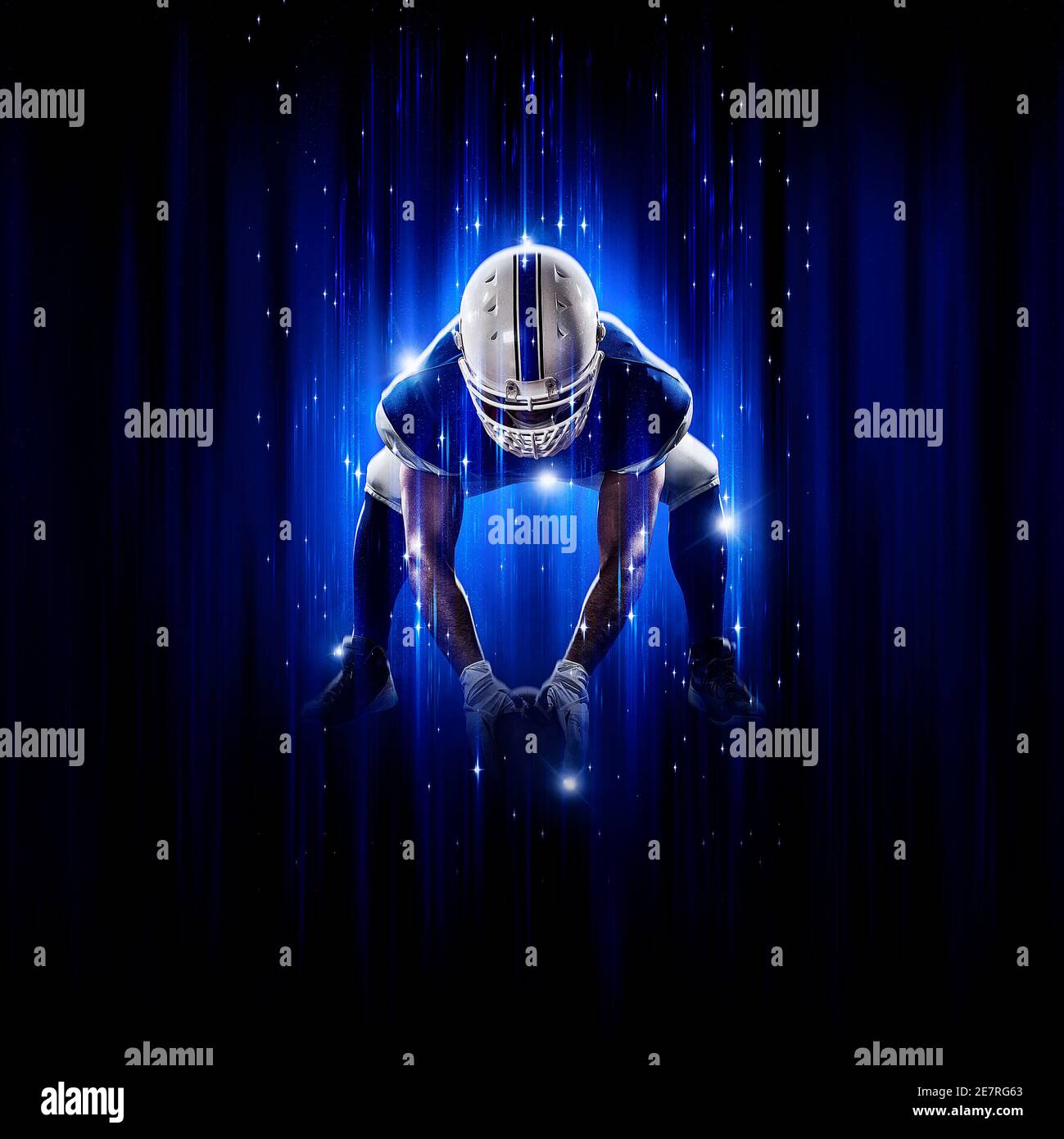 Football Player player with a superhero pose  wearing a blue uniform on a black background with blue lights. Stock Photo