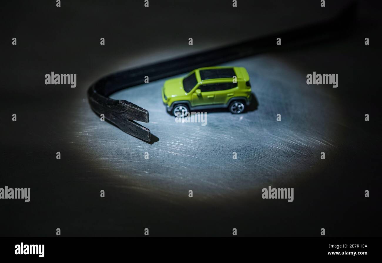 Miniature SUV and a crowbar under a beam light. Stock Photo