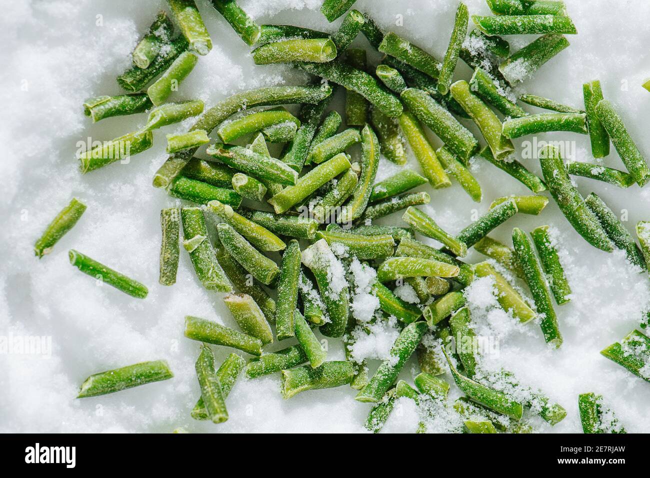 Spilled frozen green beans on a grinded ice. top view. Stock Photo