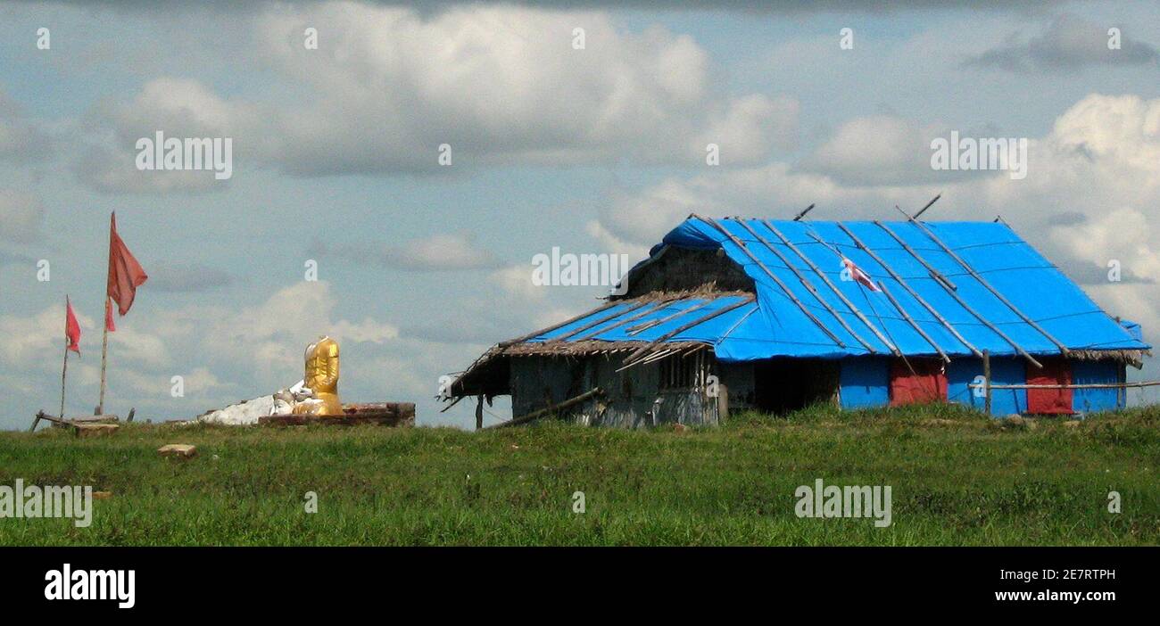 A headless Buddha statue is seen next to a house covered in tarpaulins near Labutta October 31, 2008. Six months after Cyclone Nargis slammed into the delta, killing more then 130,000 people and leaving 2.4 million destitute, farmers in Asia's one-time 'rice bowl' say they expect to produced between 30 and 50 percent less rice than normal.  Picture taken on October 31, 2008.   REUTERS/Staff   (MYANMAR) Stock Photo