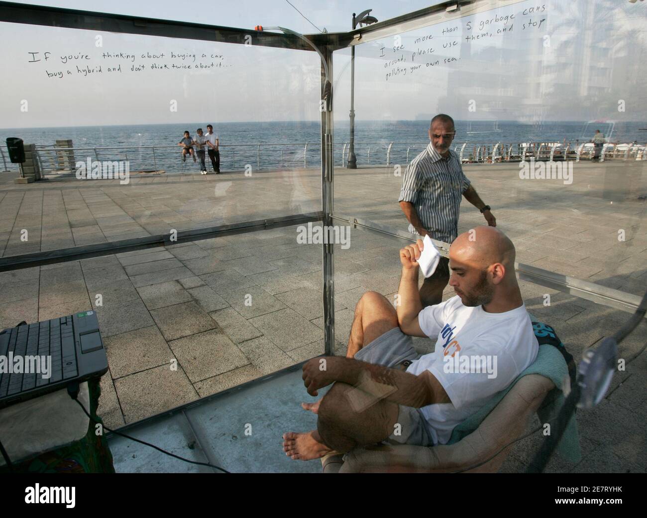 Lebanese environmental activist Rami Eid sits in a transparent cube as  people watch him at Ain al-Mrayseh corniche in Beirut, October 16, 2009.  "The man in the Cube" is a project organized