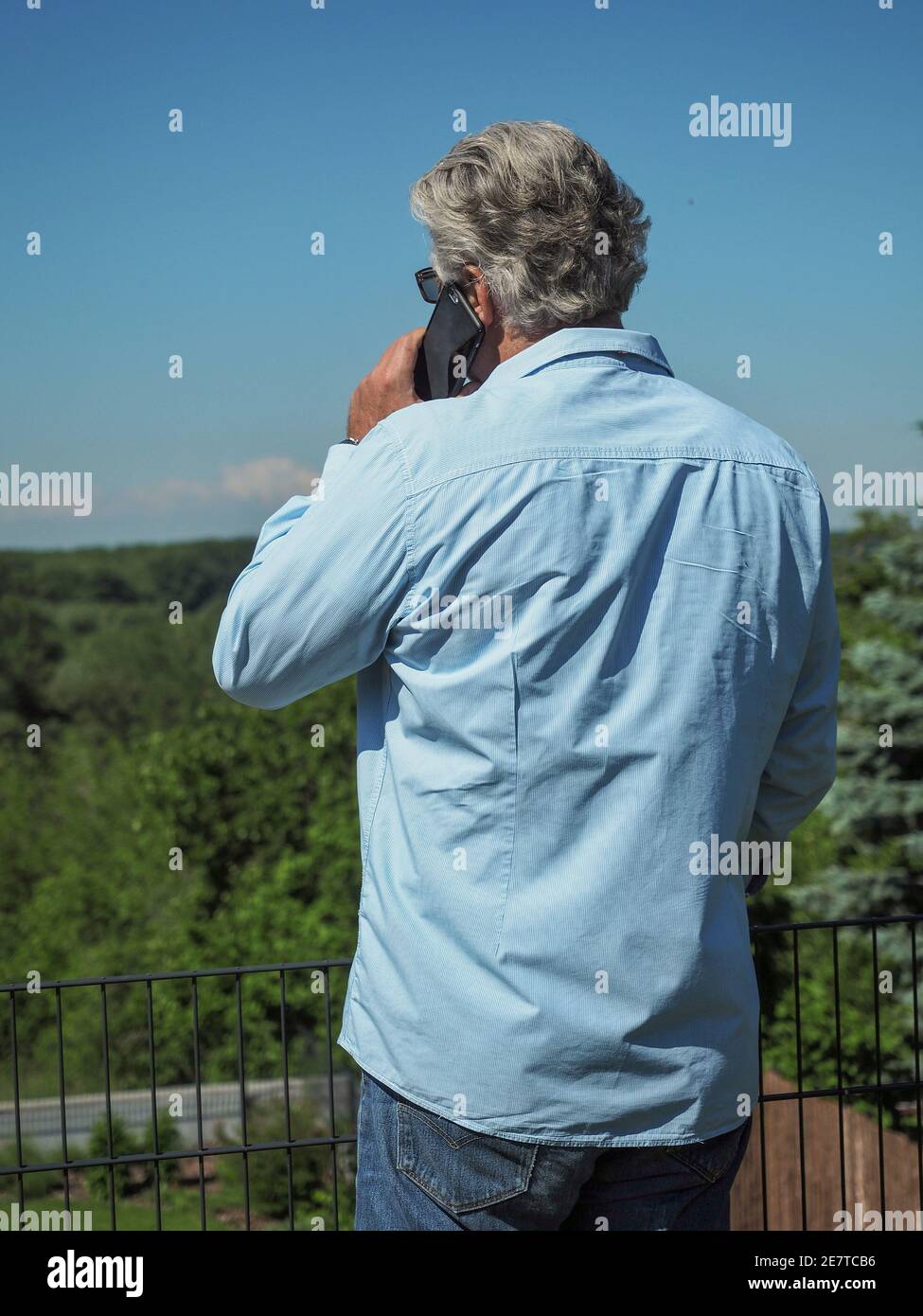 Senior businessman with grey hair stays in the garden and makes a phone call. Home office concept.  Stock Photo