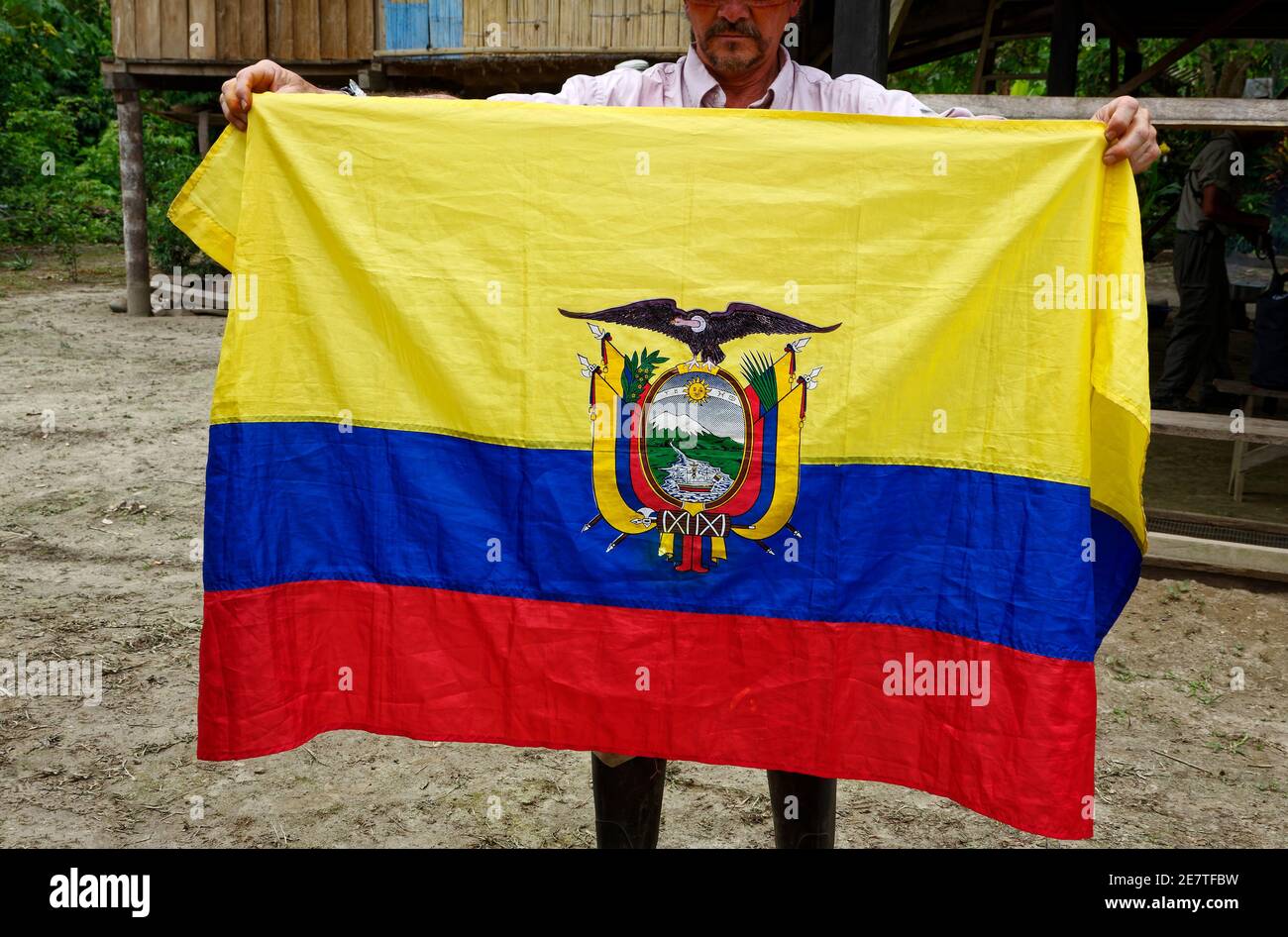 Ecuadorean flag, yellow, blue, red,coat of arms, condor with wings spread, scene, man holding, South America, Ecuador, MR Stock Photo