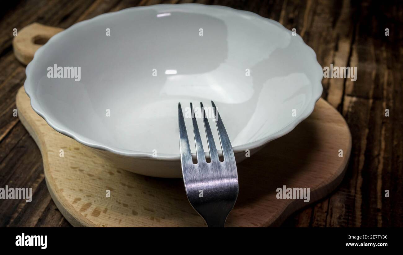 An empty plate with a fork on a wooden tray, a plate without food. Stock Photo