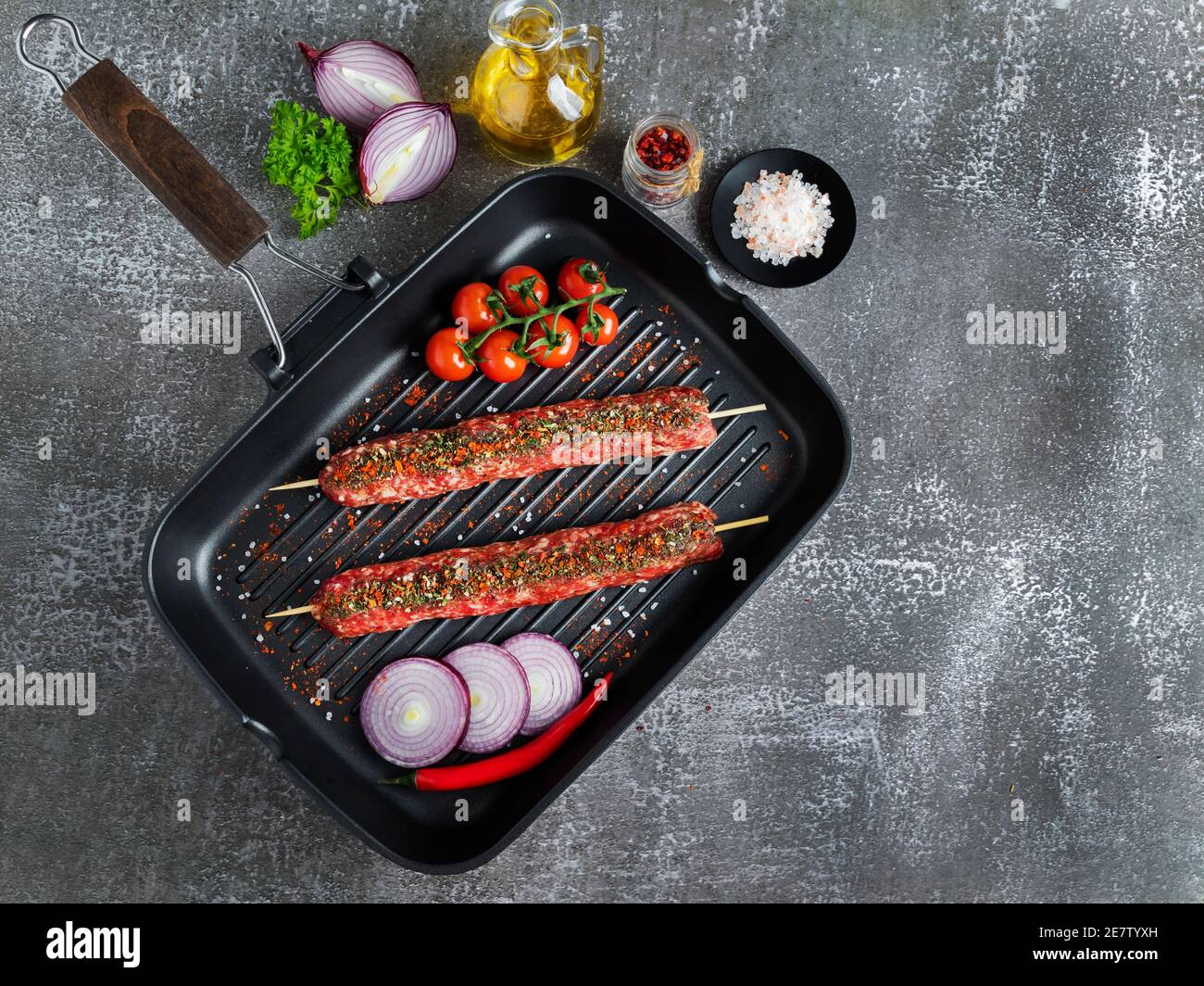 lula kebab raw meat wooden skewer on a frying pan grill, spices, top view Stock Photo