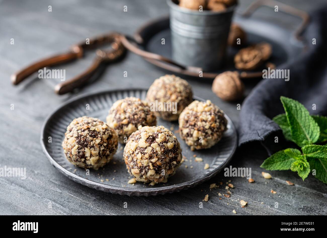 Dark chocolate truffle coated in chopped and toasted walnuts on a plate on stone background Stock Photo