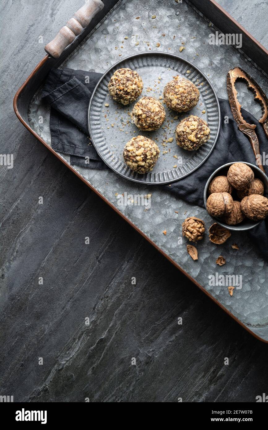 Dark chocolate truffle coated in chopped and toasted walnuts on a plate on stone background with copy space Stock Photo