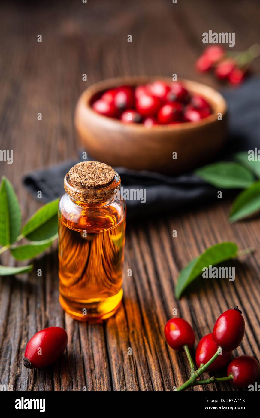 Pure rosehip seed oil in a glass bottle, remedy for skin and hair on rustic wooden background Stock Photo