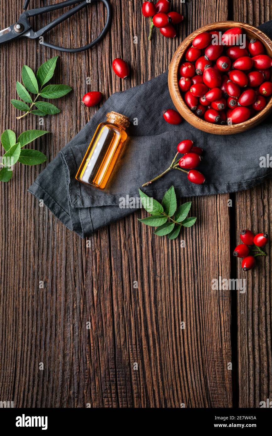 Pure rosehip seed oil in a glass bottle, remedy for skin and hair on rustic wooden background with copy space Stock Photo