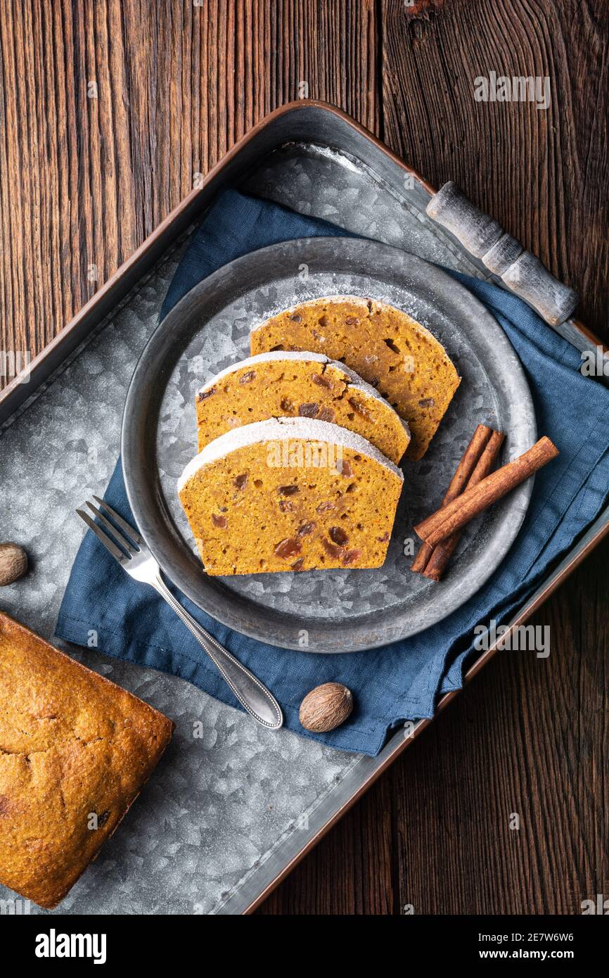 Sweet whole grain pumpkin bread slices with raisins, sprinkled with powdered sugar on rustic wooden background Stock Photo