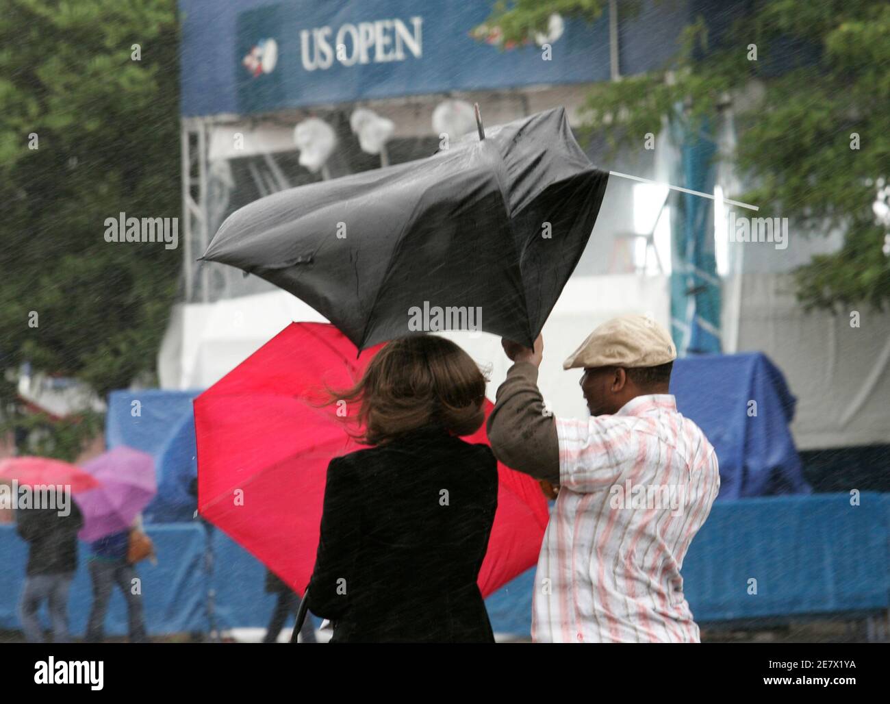 Spectators walk in the wind and rain at the U.S. Open tennis tournament in  New York, September 11, 2009. Tennis play has been suspended at the  tournament because of inclement weather. REUTERS/Eduardo