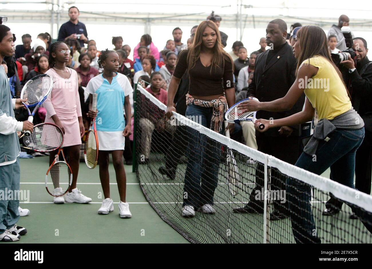 Tennis player Venus Williams (R) instructs young Washington tennis players on their technique as her sister Serena (C) looks at them during their visit to the Southeast Tennis and Learning Center in Washington December 8, 2005. The Williams sisters met with dozens of children of Washington's southeast as part of their 'Williams Sisters Tour' to help raise money for charities. REUTERS/Jason Reed Stock Photo