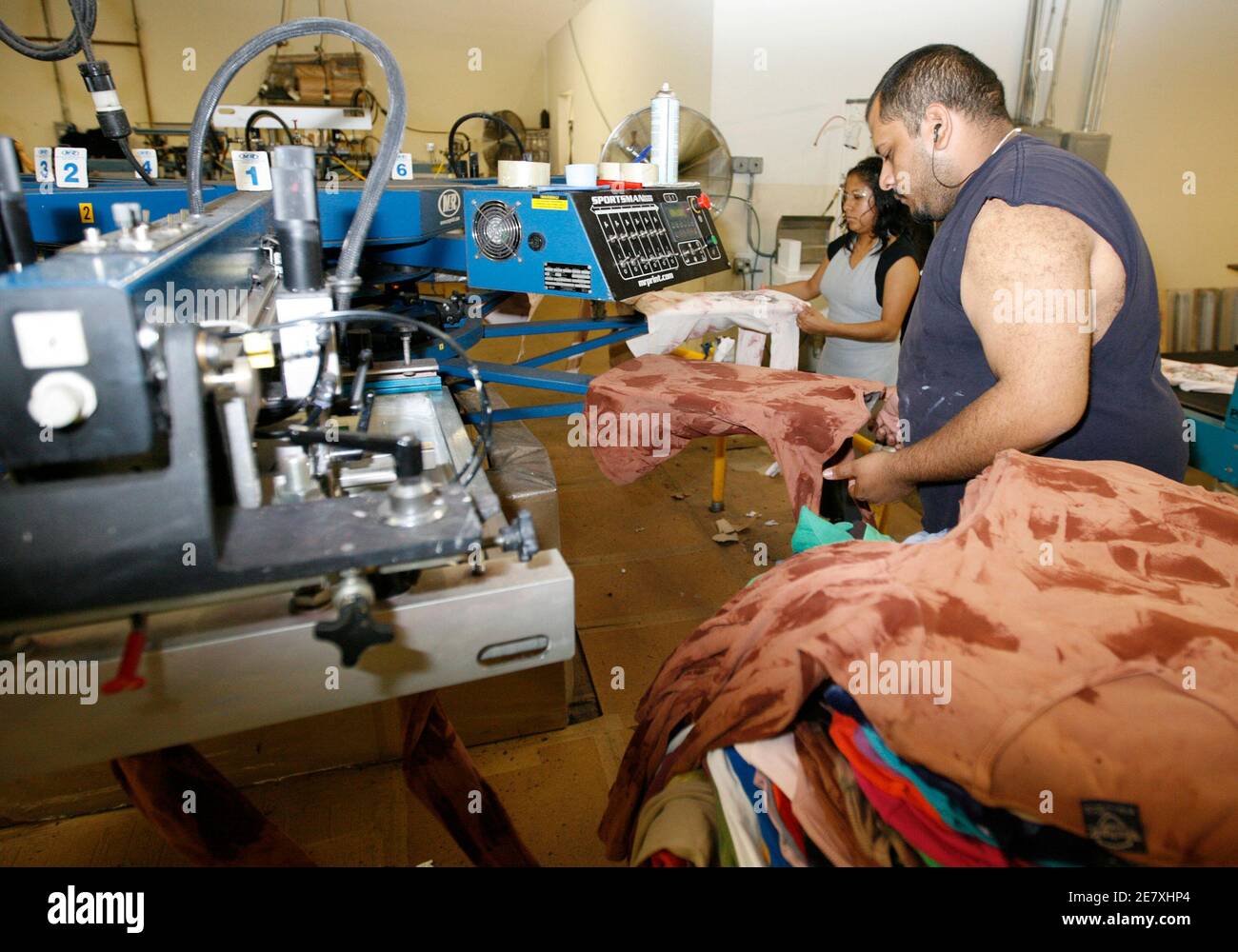 Workers feed women's t-shirts onto a machine which prints designs on the shirts at the Sledge USA clothing factory in Los Angeles October 13, 2009  U.S. store chains are hedging a major bet they made this year by slashing inventories, sometimes as much as 25 percent, to make sure they do not get stuck with a glut of merchandise for a second consecutive year.  To match feature RETAIL-HOLIDAYSALES-INVENTORY/   REUTERS/Fred Prouser   (UNITED STATES BUSINESS) Stock Photo