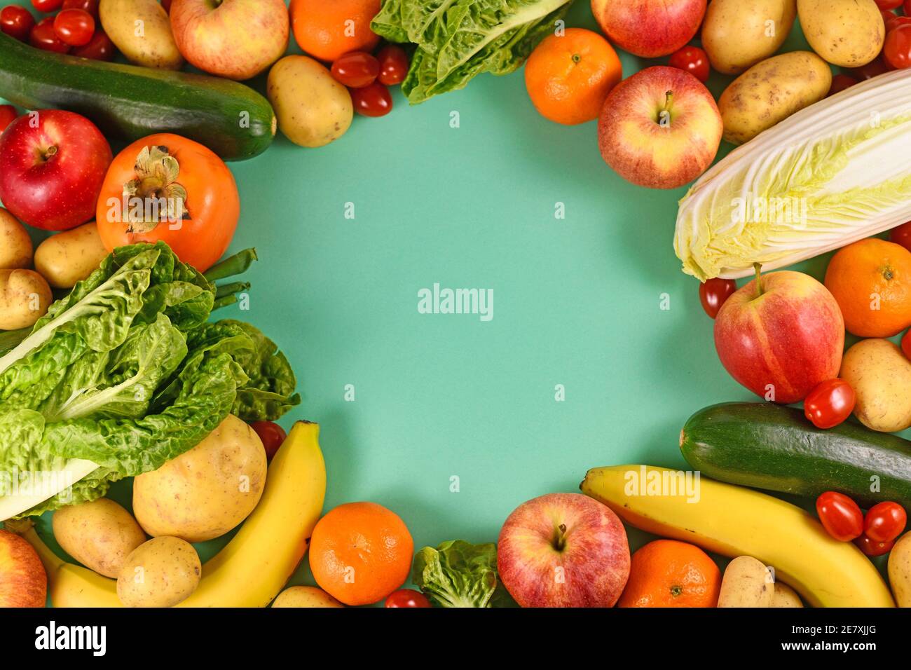 Various healthy raw fruits and vegetables with empty copy space in middle on green background