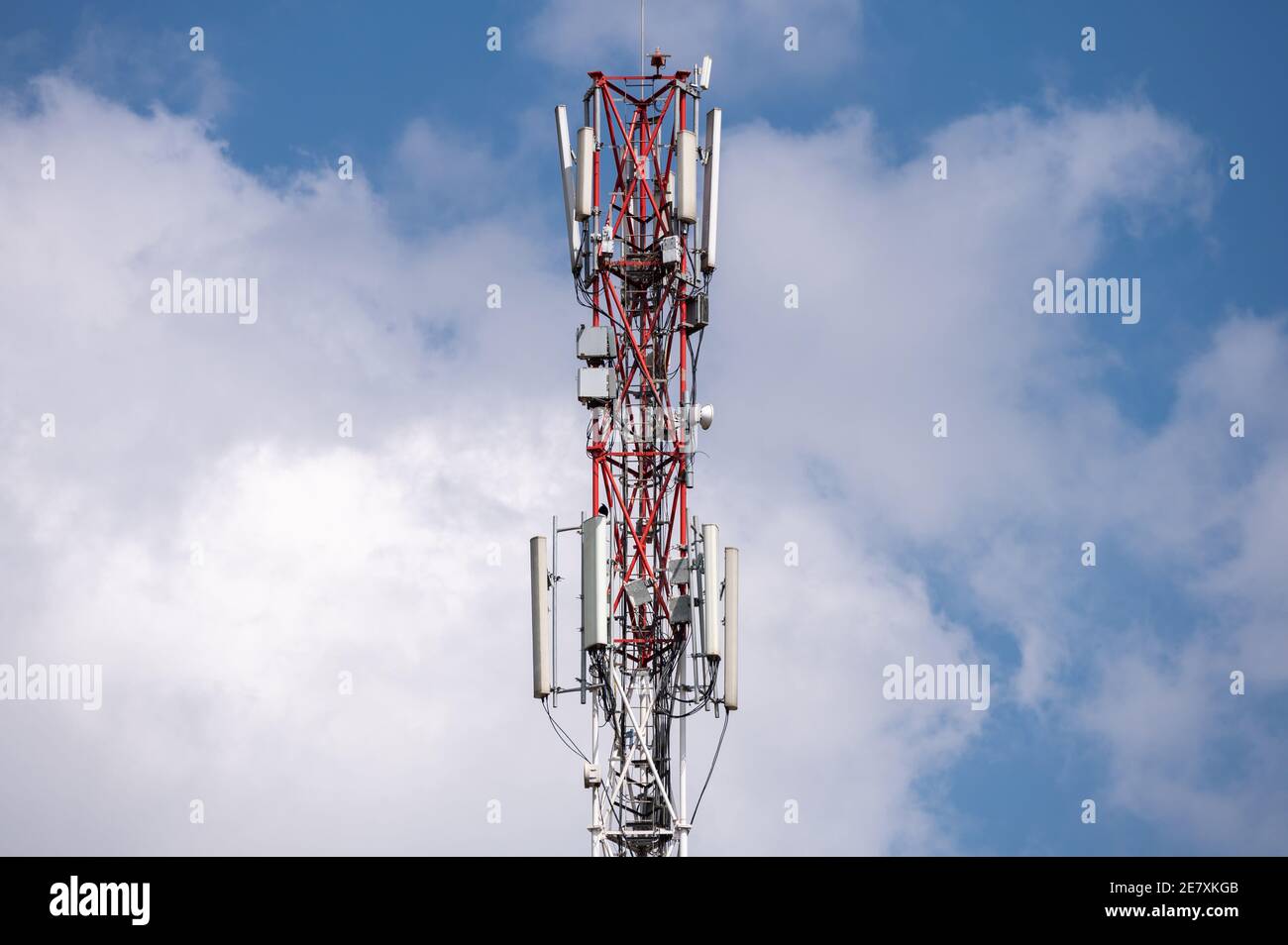 A cell phone or mobile phone antenna mast against a sunny cloudy sky Stock Photo