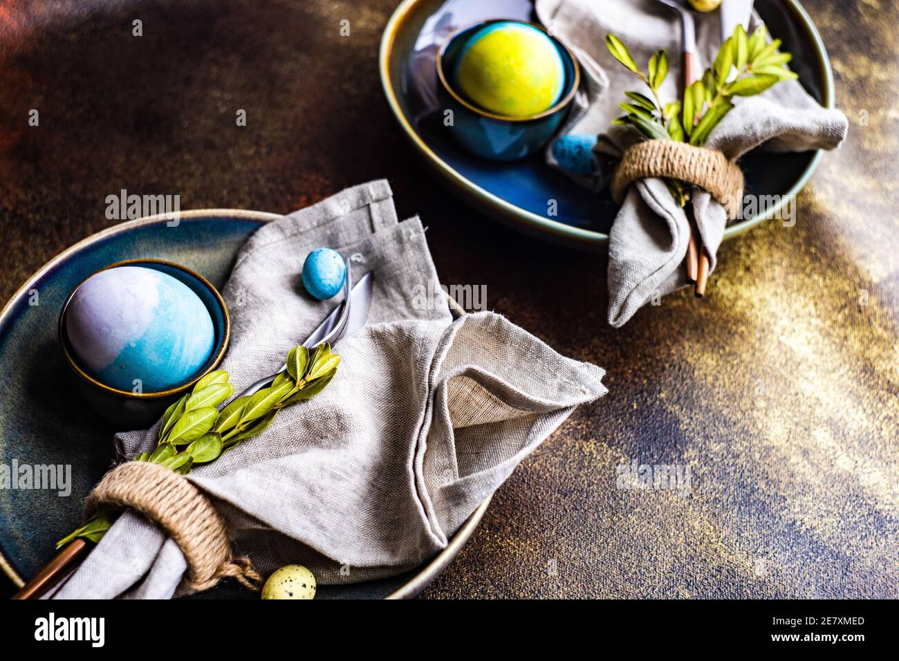 Easter table setting with colored eggs and boxwood leaves Stock Photo