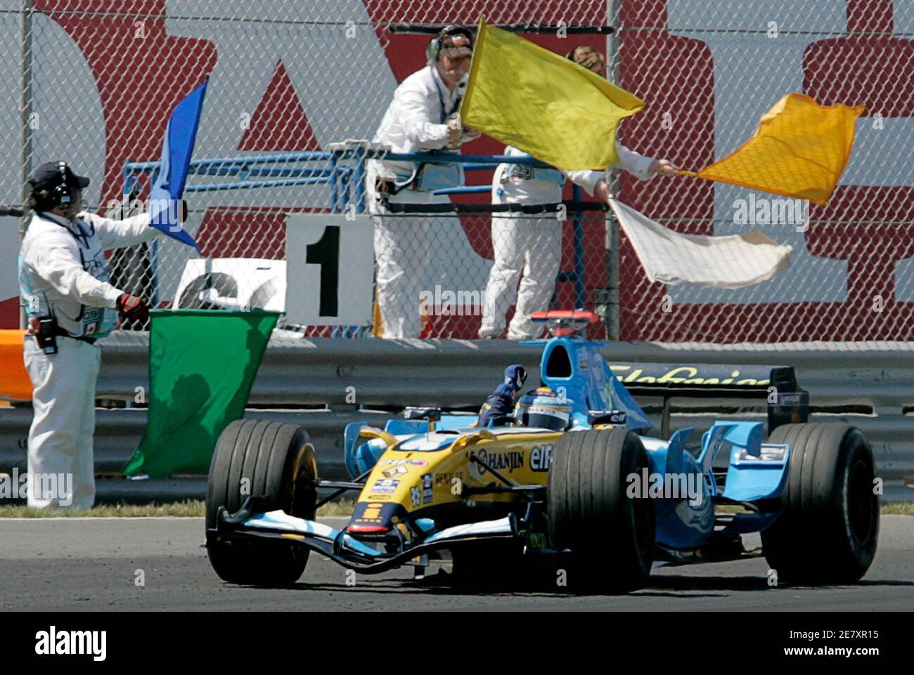 Race marshals wave their colored flags as Renault Formula One Driver Fernando Alonso of Spain drives past after crossing the finish line to win the Canadian Formula One Grand Prix in Montreal June 25, 2006.  REUTERS/J.P. Moczulski (CANADA) Stock Photo