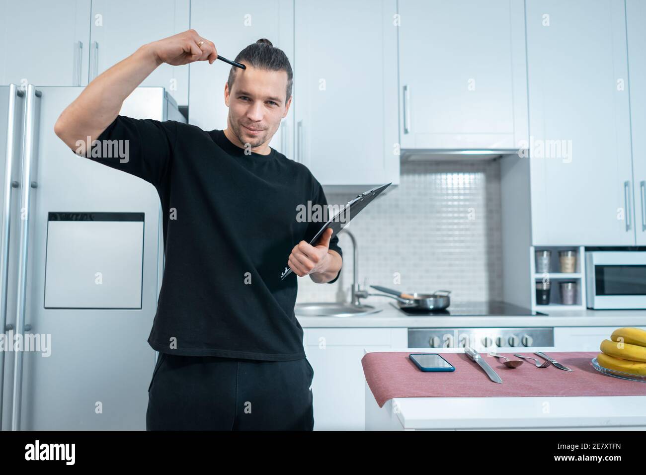 fitness nutritionist man count calories with clipboard at modern kitchen concept Stock Photo