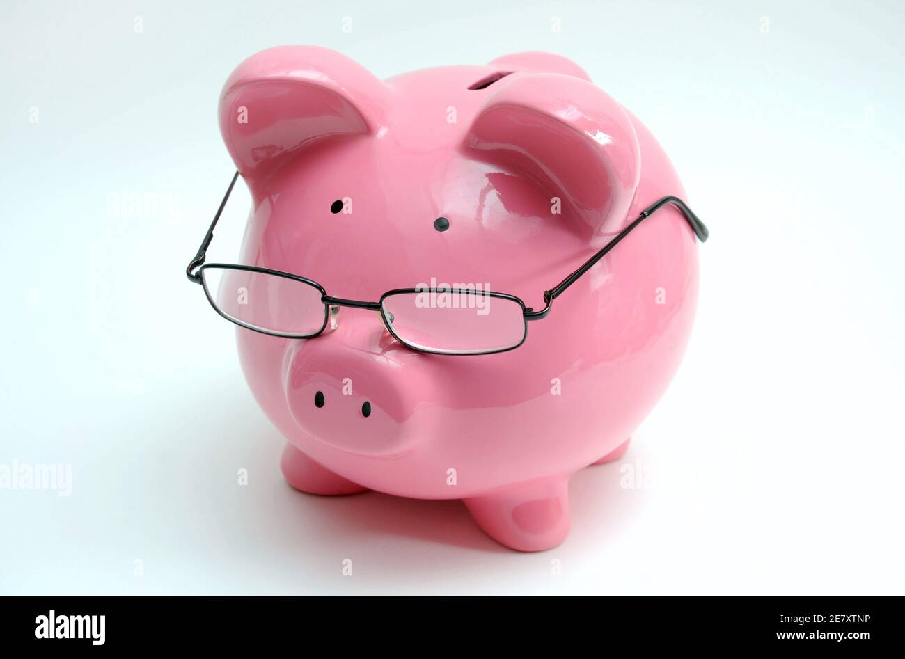 PIGGY BANK WEARING SPECTACLES RE SAVINGS RETIREMENT PLAN PENSIONS OLD AGE ETC UK Stock Photo
