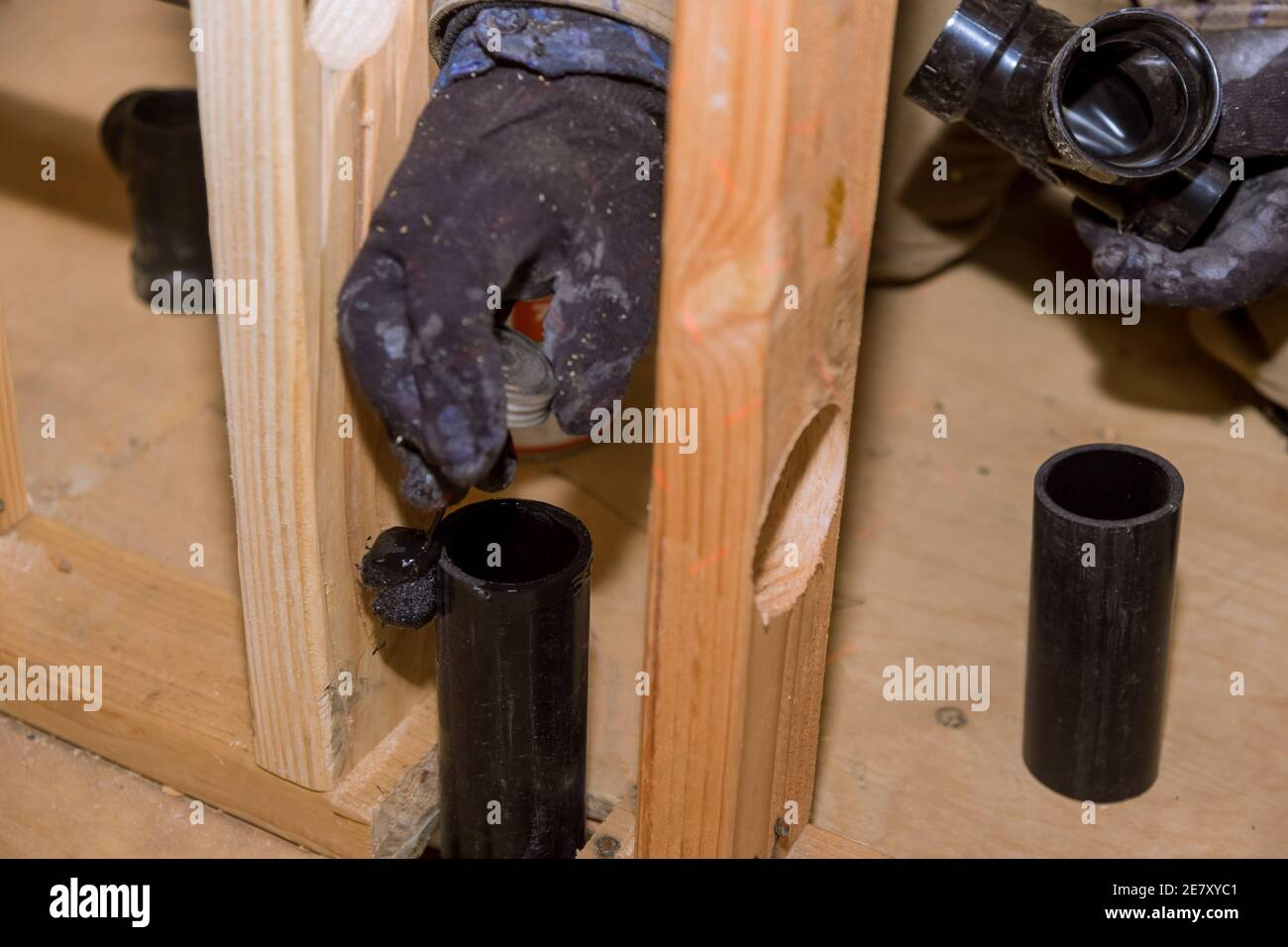 PVC plastic sewer toilet drain pipe in the plumber gluing, on wooden