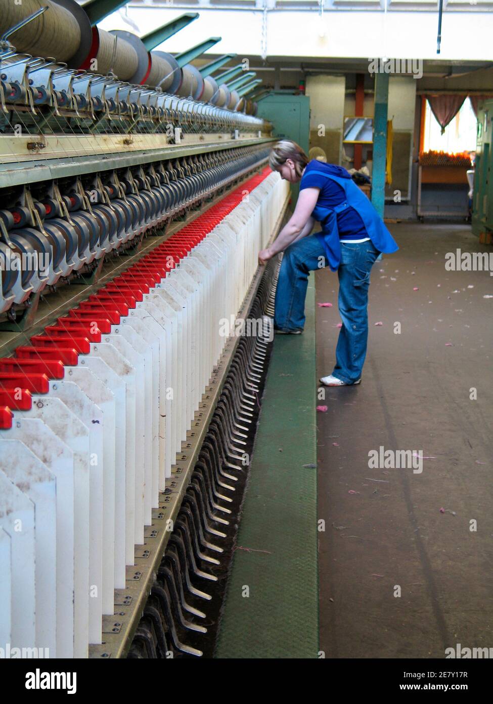 A worker checks spinning machines, that twist fibres of cashmere together to give them strength and wind them onto bobbins, at Scottish textiles company Johnstons in Elgin, Scotland May 20, 2008. Faced with the threat of cheap outsourcing and mass manufacturing, the 211-year old Johnstons family-owned firm has shifted focus from supplying the high street to providing instead top quality fabric and garments for luxury brands such as Louis Vuitton, Channel, and Hugo Boss. Photo taken May 20, 2008. To match feature BRITAIN-TEXTILES/ REUTERS/Sarah Marsh (BRITAIN) Stock Photo