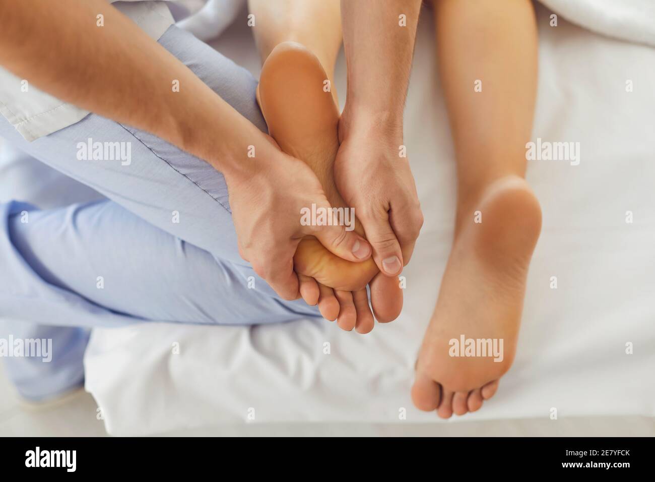 Hands of doctor masseur making manual massage of feet for lying woman Stock Photo