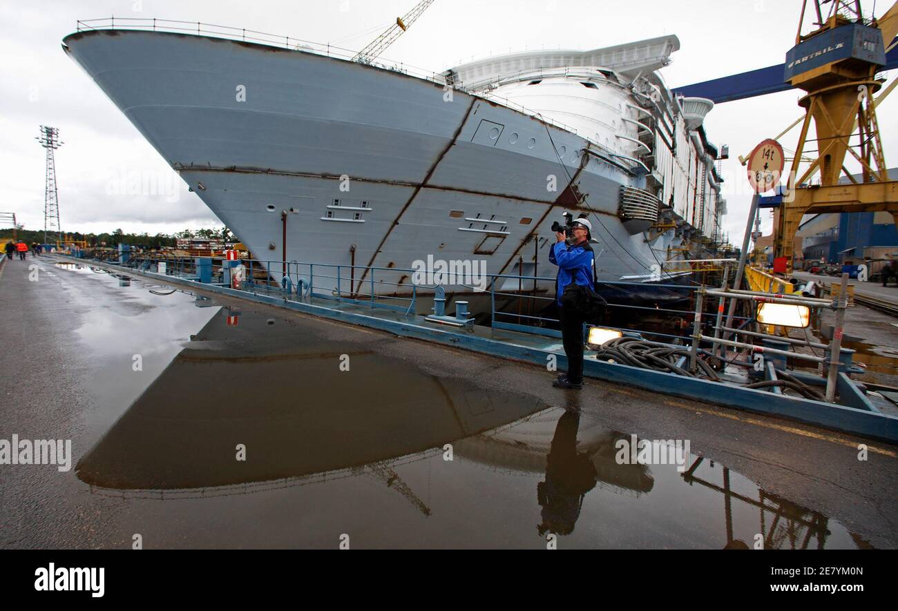 A photographer stands in front of the Royal Caribbean's Allure of the Seas cruise ship as he takes pictures of her twin sister, the Oasis of the Seas, while both ships are under construction at the STX Europe shipyard in Turku August 27, 2009. The Oasis of the Seas, a 225,000-ton ship, will be the largest cruise vessel ever built and will be able to accommodate over 6,000 passengers. REUTERS/Bob Strong  (FINLAND SOCIETY TRAVEL) Stock Photo
