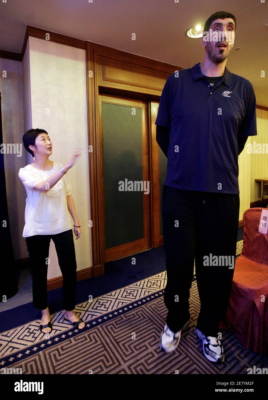 A woman gestures to former Washington Bullets player Gheorghe Muresan of Romania as he arrives for a news conference in Beijing, September 8, 2009. The Washington Wizards are commemorating the 30th anniversary of the team's 1979 trip to China with a 10-day, five-city goodwill tour. The Wizards were previously known as the Washington Bullets.   REUTERS/Jason Lee (CHINA SPORT BASKETBALL) Stock Photo