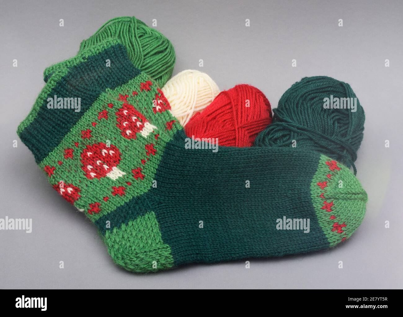 a woolen socks with amanita and skeins of thread Stock Photo
