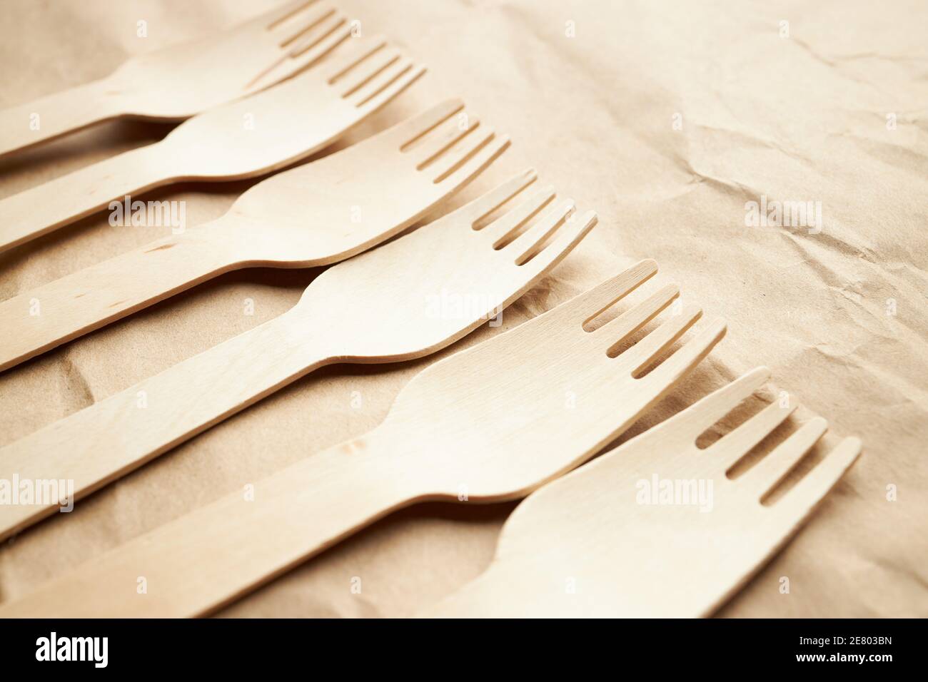 diagonal line made by pile of disposable eco friendly wooden forks on paper background. kitchenware utensils. eco friendly concept. space for text Stock Photo