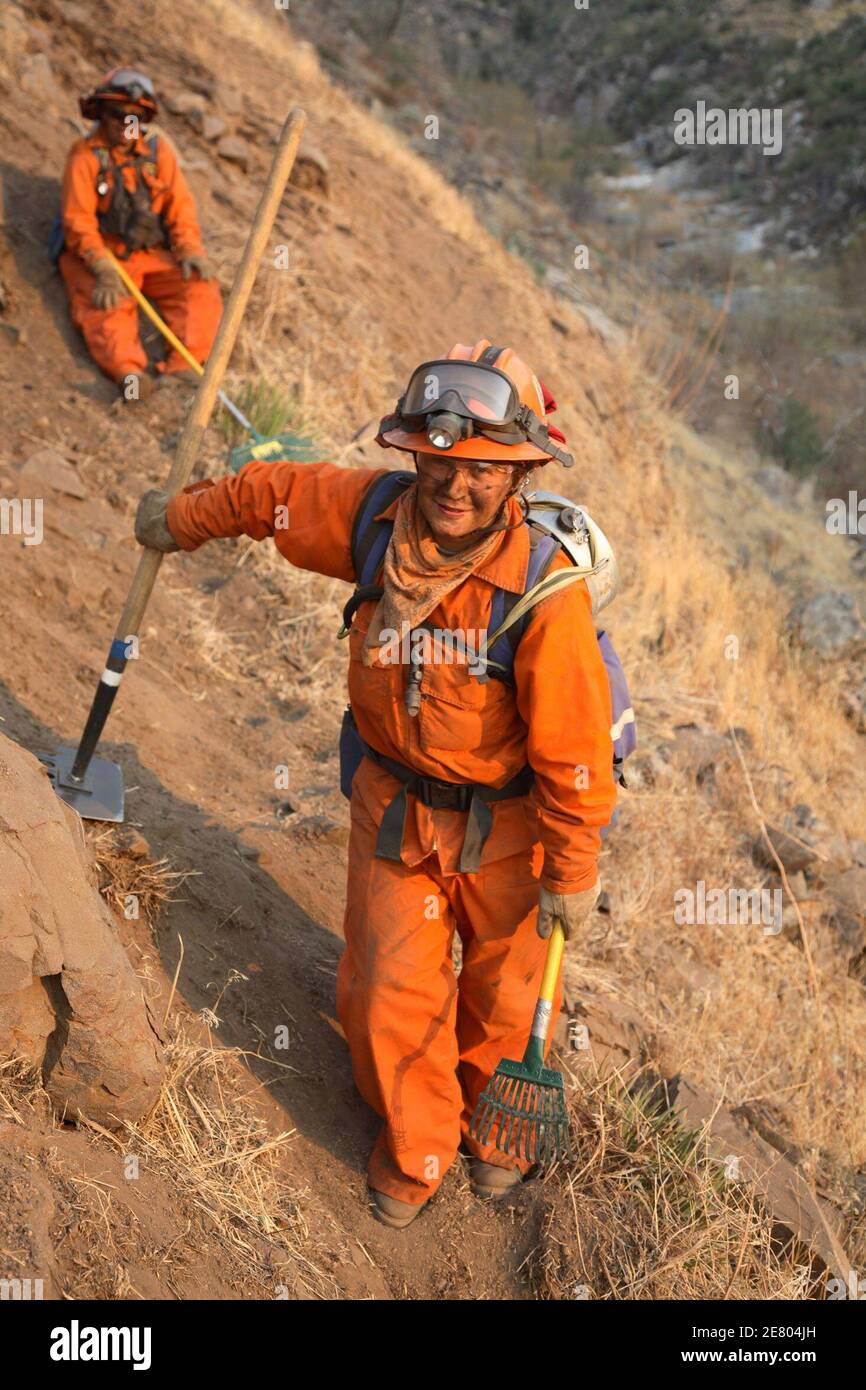Female prisoners working in a remote mountainous area of the Witch Fire past Santa Ysabel, California to build a protection line against spreading fire, October 25, 2007. Of about 9,000 firefighters battling the southern California flames, nearly 3,000 are inmates. The prisoners typically get two days off their sentence for each on the fire lines. About 300 are from all-women prisoner brigades. Picture taken October 25, 2007.    REUTERS/Adam Tanner       (UNITED STATES) Stock Photo