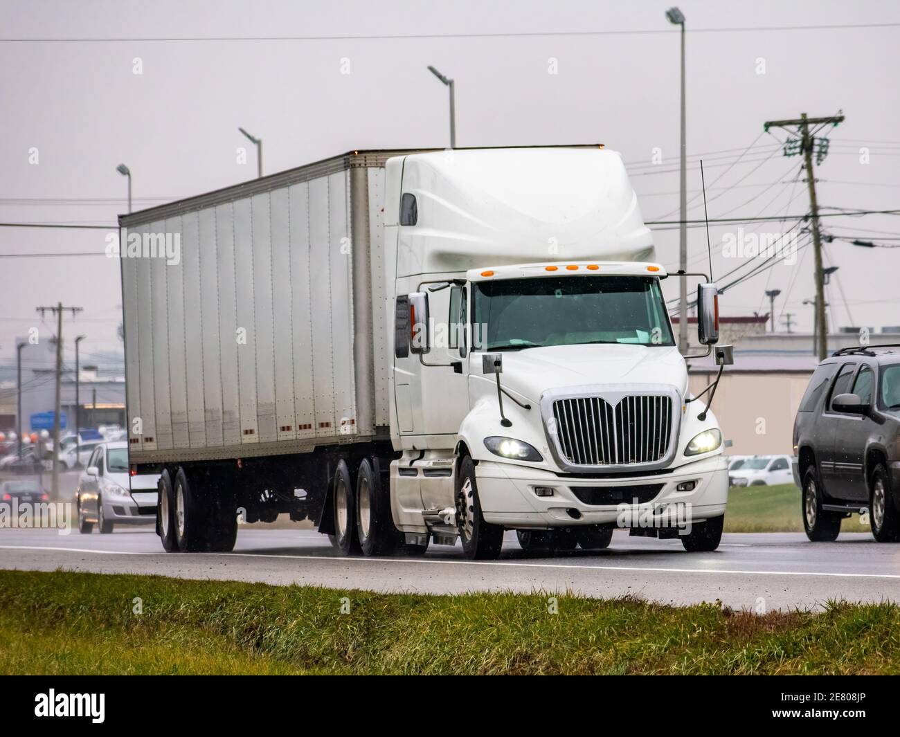 Horizontal shot of a generic white 18 wheeler in wet traffic during winter. Stock Photo