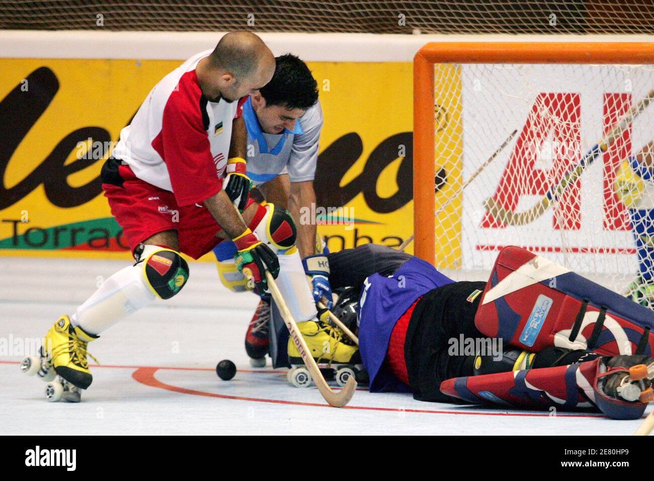 Mozambique goalie Armando Queiroz (on floor) stops a shot by Andorran  defenseman Ramon Bassols Dachs (C) as Mozambique defenseman Bruno Pimentel  (L) helps on the play in the first period of their