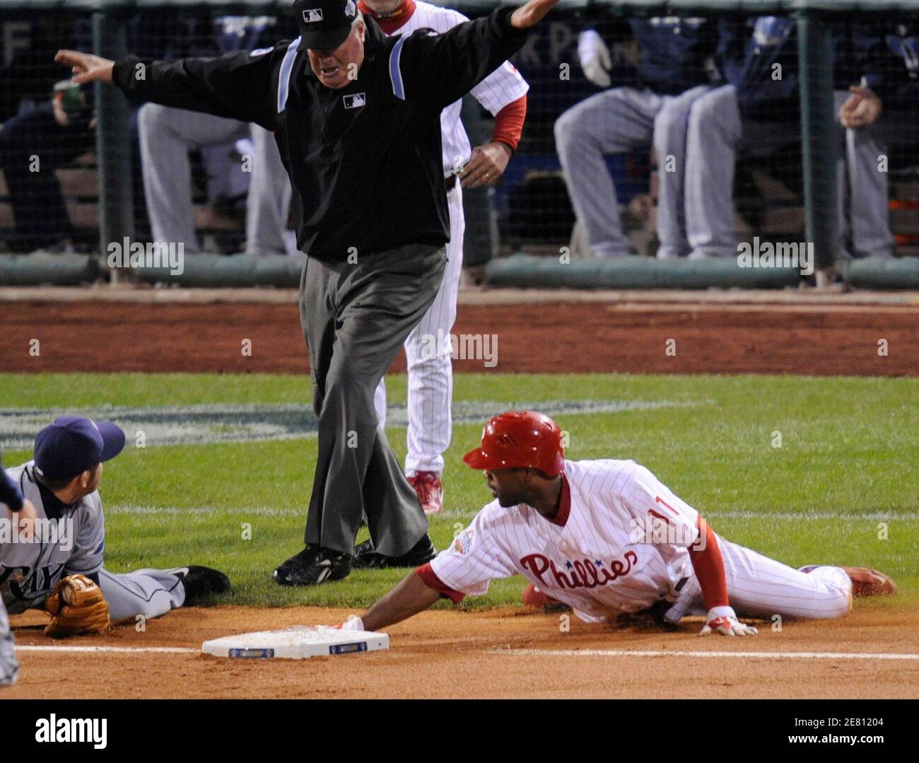 Third base umpire Tim Welke (C) signals Philadelphia Phillies baserunner  Jimmy Rollins (R) safe after a run down between home plate and third base, in  the first inning in Game 4 of