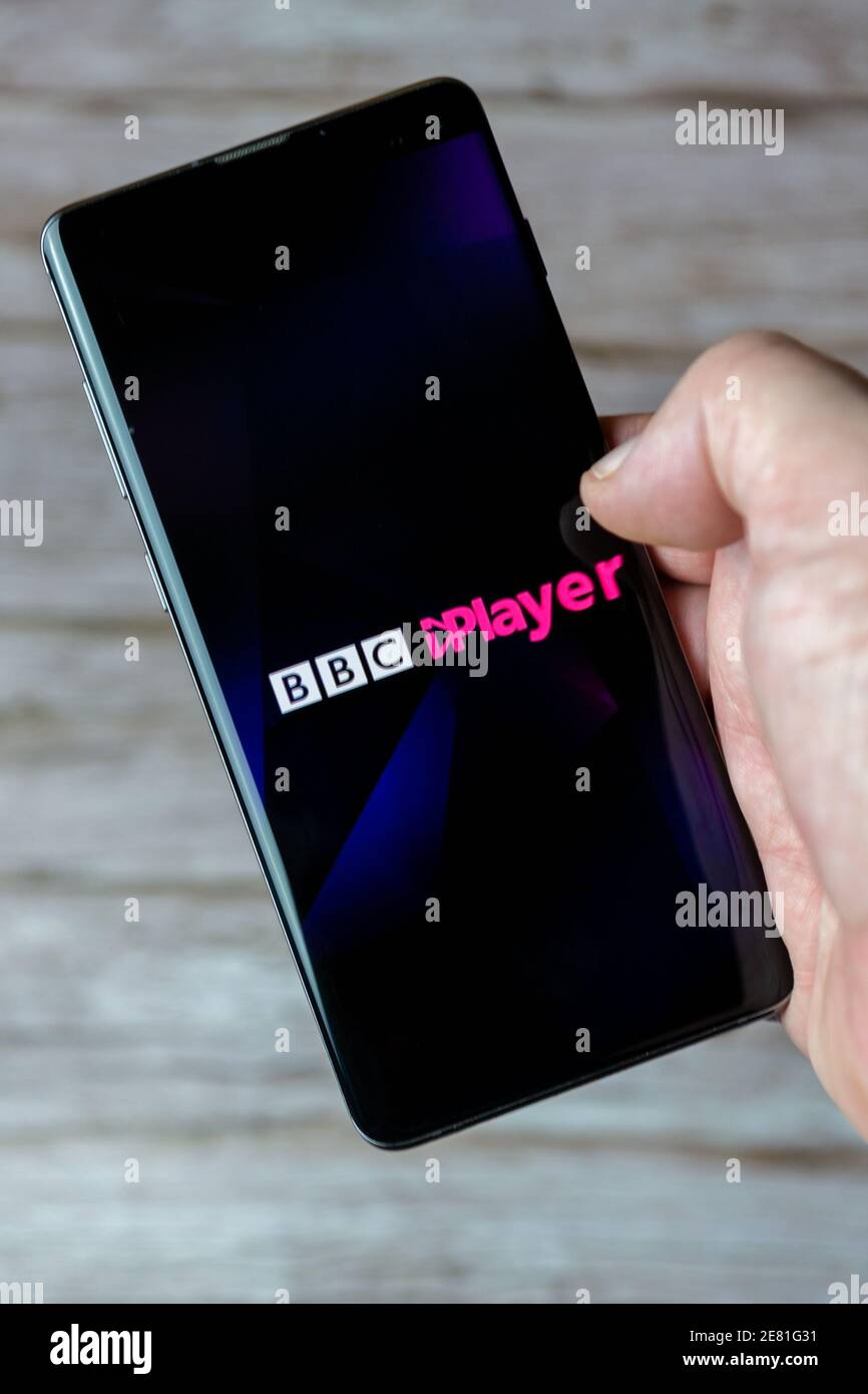 A hand holding a mobile phone or cell phone with the BBC Iplayer app open on screen Stock Photo