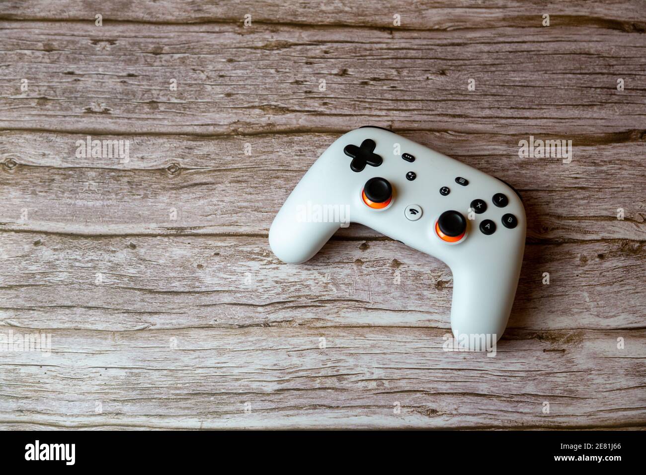 A Google Stadia controller laid on a wooden table shot from above Stock Photo