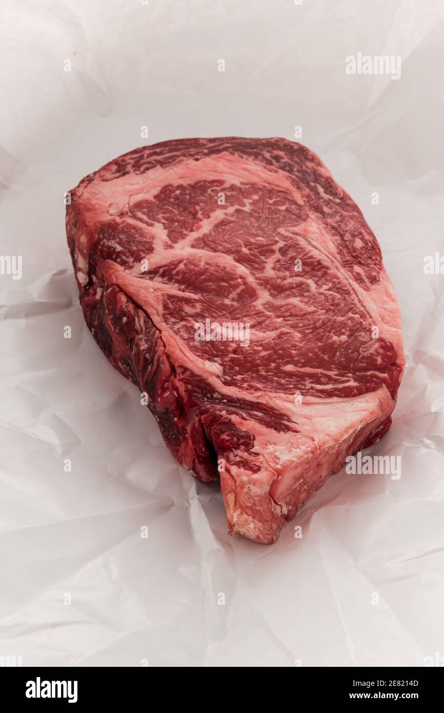 A raw New York strip Ribeye steak thick steak on paper that its wrapped
