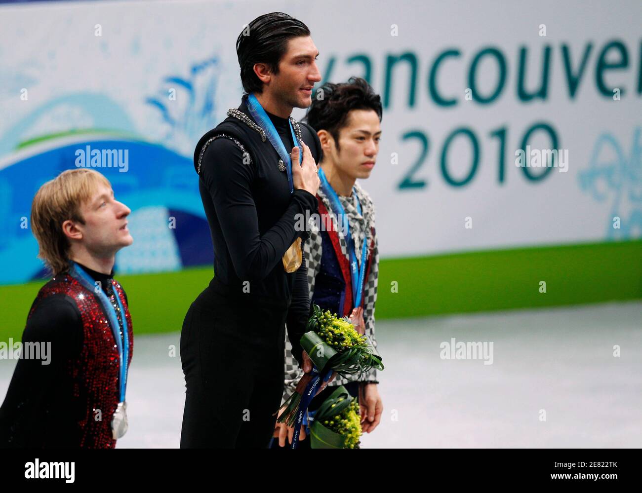 gold medallist evan lysacek c of the u s puts his hand on his chest as he stands between silver medallist evgeni plushenko l of russia and bronze medallist daisuke takahashi of japan