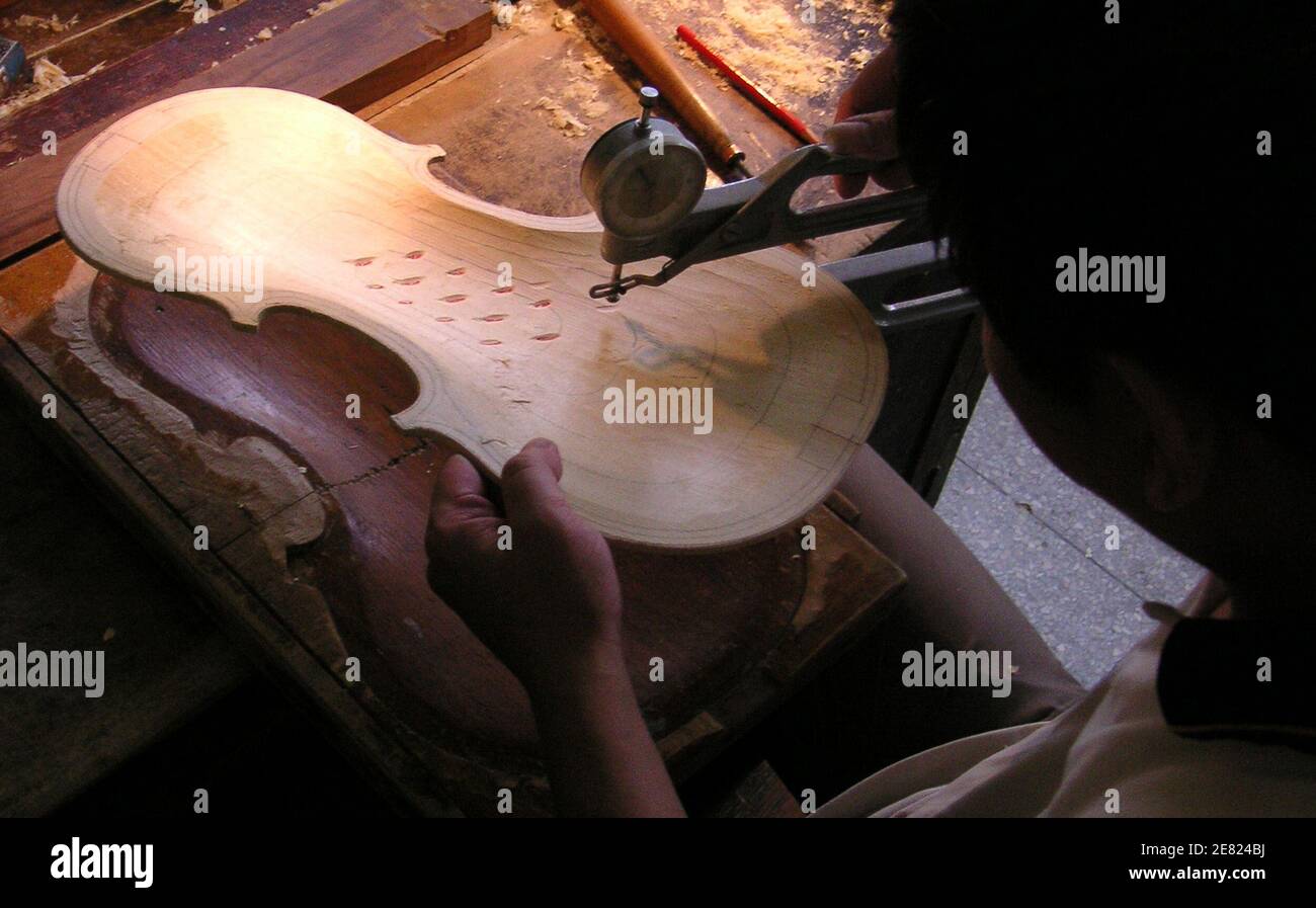 Zhang Qing, who is studying to become a violin maker, works on a violin at the workshop of Shanghai Lark Golden Bell Music Instruments August 4, 2005. From bustling Shanghai to thriving Guangzhou, thousands of factories fashion up to 1 million instruments a year mostly bound for the U.S. and European markets, ranging from pedestrian students' violins to rarefied ones used in concerts that bear names like Andreas Eastman, Johannes Kohr and Andrew Schroetter. Picture taken August 4, 2005. To match feature LEISURE-CHINA-VIOLINS REUTERS/Jerker Hellstrom  CC/YH Stock Photo