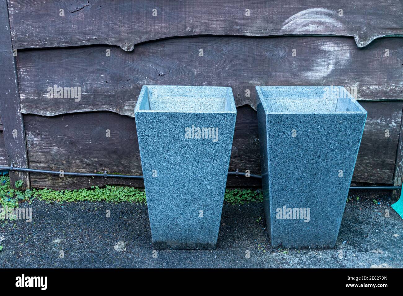a close up view of two granite plant pots sitting new to a wooden fence Stock Photo