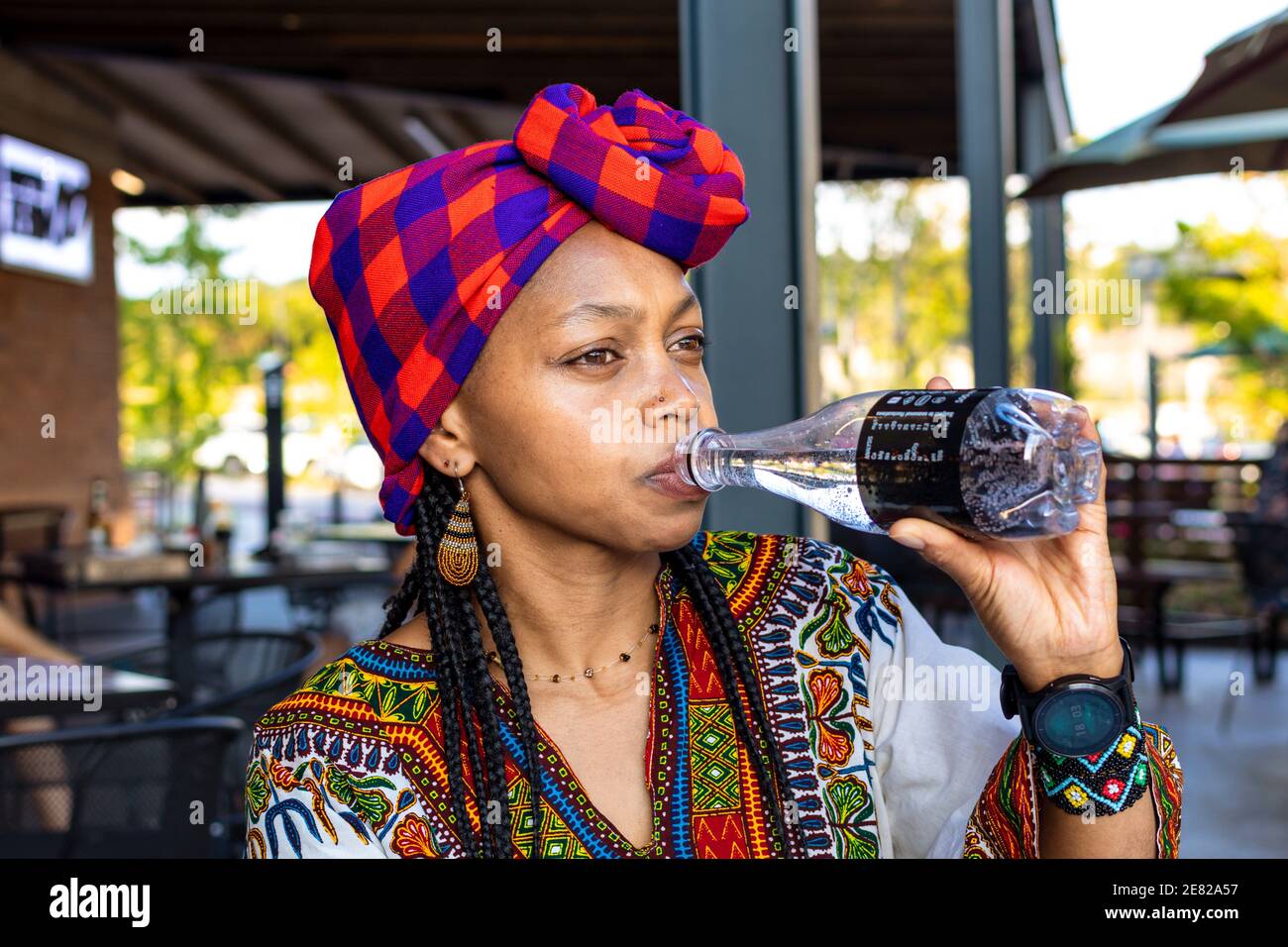 Beautiful african lady wearing a doek or headcover drinking sparkling water Stock Photo