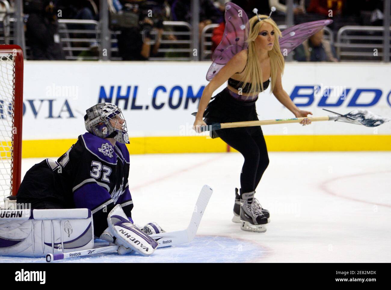Los Angeles Kings goalie Jonathan Quick stretches during a timeout as a  woman dressed in a Halloween costume cleans the ice during the first period  of their NHL hockey game against the